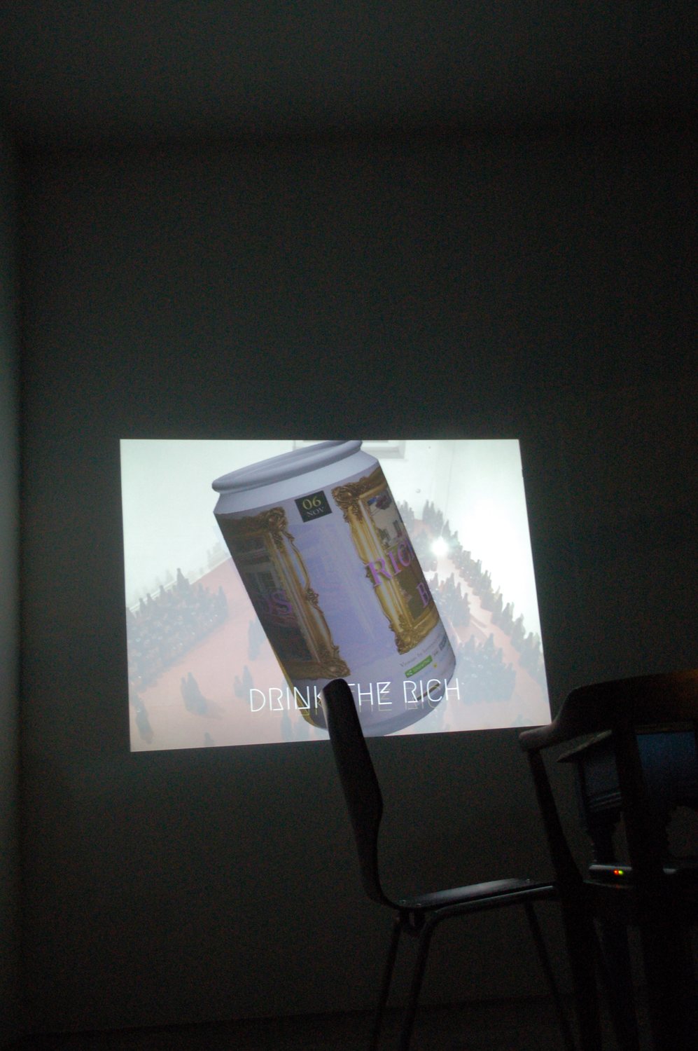 The beer can projected large on the wall in the dark room, DRINK THE RICH